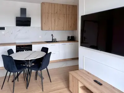 a kitchen with a table and chairs and a television at Modern Blue Apartment in Kraków