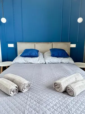 a bed with two pillows and towels on it at Modern Blue Apartment in Kraków