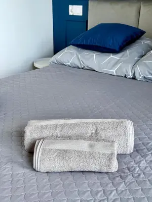 two towels on a bed with a blue pillow at Modern Blue Apartment in Kraków