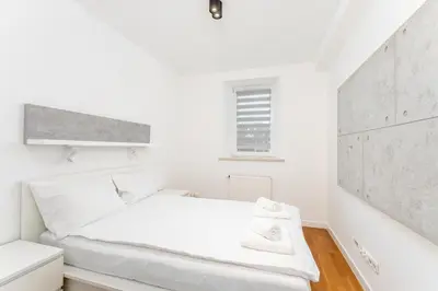 a white bedroom with a bed and a window at Ariańska Comfort Apartment by BookingHost in Kraków