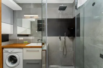 a bathroom with a shower and a washing machine at Ariańska Comfort Apartment by BookingHost in Kraków
