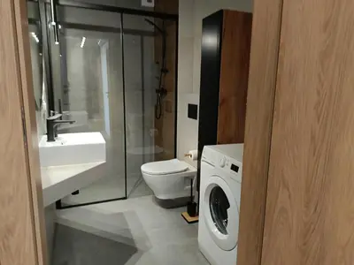 a bathroom with a toilet sink and a washing machine at Cracowapart Sunny Point in Kraków