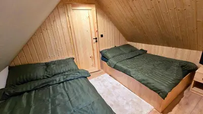 two beds in a room with wooden walls at Leśna Enklawa pod Wielką Górą in Pisarzowa
