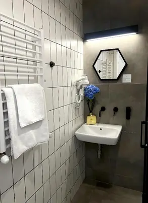 a white tiled bathroom with a sink and a mirror at Susan Apartaments Kraków Kazimierz in Kraków