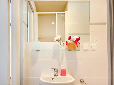 a table with a vase of flowers and a tv on a wall at Smart Studio for 3 guests 8 min to Main Square in Kraków