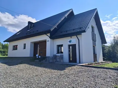 a white house with a black roof at Bądź blisko in Jurków