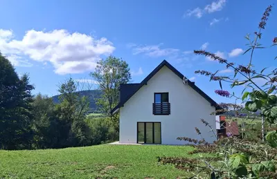 a white house on top of a grassy hill at Bądź blisko in Jurków