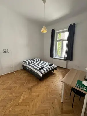 a bedroom with a bed and a table and a window at Fantastic-Inn Kraków - Krasińskiego in Kraków