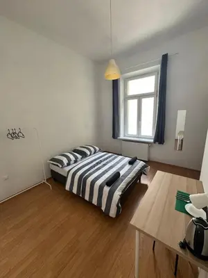 a bedroom with a bed and a table and a window at Fantastic-Inn Kraków - Krasińskiego in Kraków