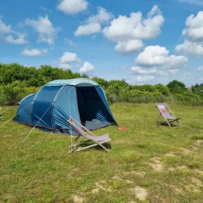 a blue tent and two folding chairs in a field at Uszate Ranczo Malinka in Rybna