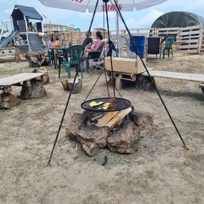 a campfire with a grill and people sitting at tables at Uszate Ranczo Malinka in Rybna