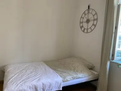 a bedroom with a bed and a clock on the wall at Luna Rooms in Kraków