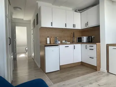 a kitchen with white cabinets and wooden floors at Old Town Escape in Kraków