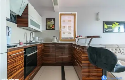 a kitchen with wooden cabinets and a black appliance at Apartment with living room, kitchen, bedroom, bathroom in amazing neighborhood in Kraków