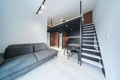 a living room with a couch and a staircase at Zabłocie Luxury Apartment WAWELOFTS in Kraków
