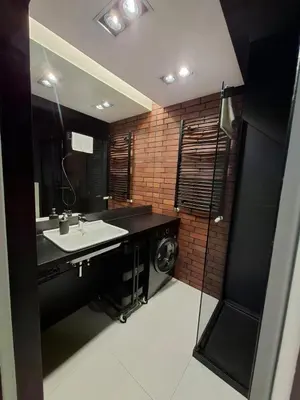 a bathroom with a sink and a washing machine at Zabłocie Luxury Apartment WAWELOFTS in Kraków