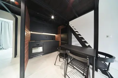 a kitchen with black cabinets and a table and chairs at Zabłocie Luxury Apartment WAWELOFTS in Kraków