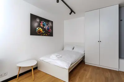 a white bedroom with a bed and a table at Topolowa Modern Studio by BookingHost in Kraków