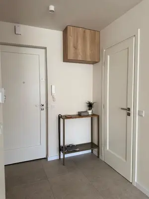 a hallway with two white doors and a shelf with shoes at Olszańska Gem in Kraków