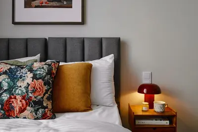 a bed with a gray headboard and a yellow pillow at UR4N Apartment - Konarskiego in Kraków