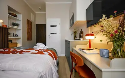 a bedroom with a bed and a desk with a lamp at UR4N Apartment - Konarskiego in Kraków