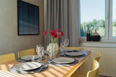 a dining room table with a vase of red flowers at Białoprądnicka - Stay&Park in Kraków