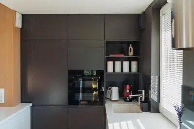 a kitchen with black cabinets and a sink at Białoprądnicka - Stay&Park in Kraków