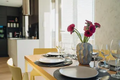 a dining room table with a vase with flowers in it at Białoprądnicka - Stay&Park in Kraków