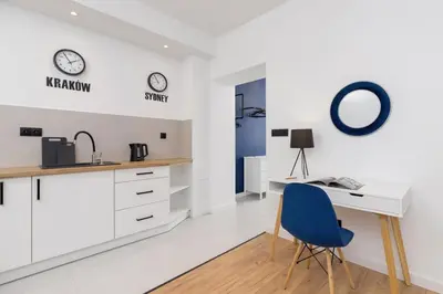 a white kitchen with a desk and a blue chair at Studio Cracow Starowiślna by Noclegi Renters in Kraków