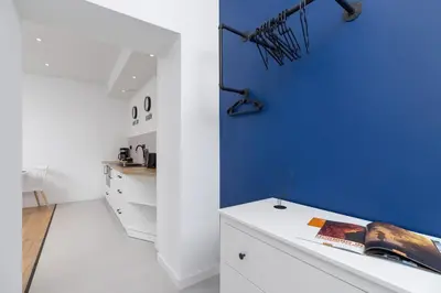 a room with a blue wall and a white table at Studio Cracow Starowiślna by Noclegi Renters in Kraków