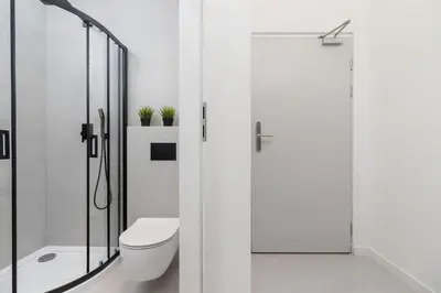 a white bathroom with a toilet and a shower at Studio Cracow Starowiślna by Noclegi Renters in Kraków