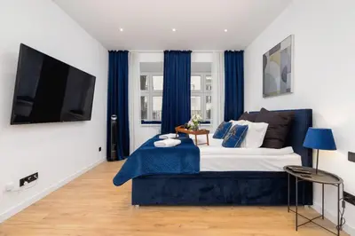 a bedroom with a large bed with blue curtains at Studio Cracow Starowiślna by Noclegi Renters in Kraków