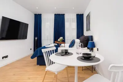 a living room with a white table and a tv at Studio Cracow Starowiślna by Noclegi Renters in Kraków