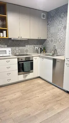 a kitchen with white cabinets and a wooden floor at Cozy Mood Apartment Cracow in Kraków