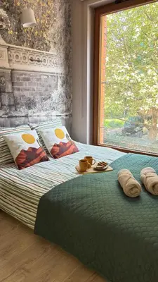 a bed with a green comforter and a window at Cozy Mood Apartment Cracow in Kraków