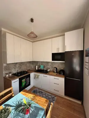a kitchen with white cabinets and a table and a black refrigerator at Apartament Marysia in Oświęcim