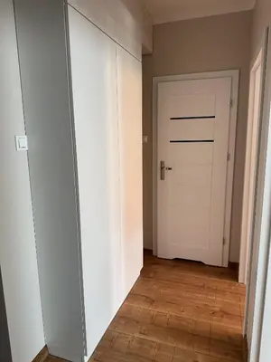 a hallway with a white door and a wooden floor at Apartament Marysia in Oświęcim