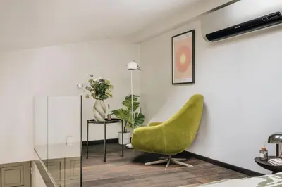 a bedroom with a green chair and a table at Wolnica No 11 Residence in Kraków