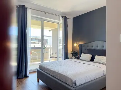 a bedroom with a large bed and a balcony at Krakowska Konstelacja Apartament premium in Kraków
