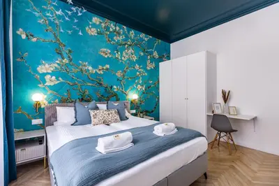 a bedroom with a large bed with a blue wall at BoB Elite - Floriańska in Kraków
