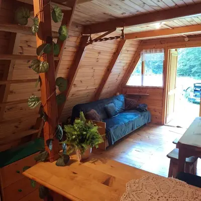 a living room of a log cabin with a blue couch at Przytulny domek na skraju lasu in Tabaszowa