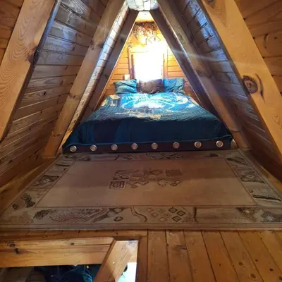 a bed in the attic of a log cabin at Przytulny domek na skraju lasu in Tabaszowa