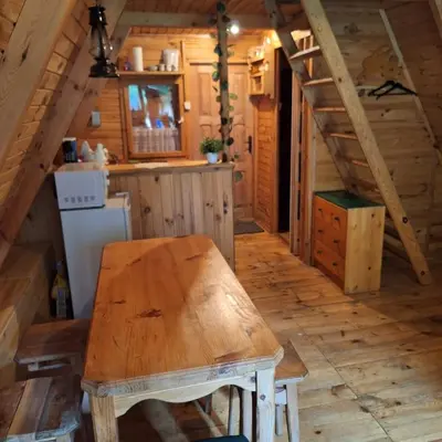 a kitchen with a wooden table in a cabin at Przytulny domek na skraju lasu in Tabaszowa