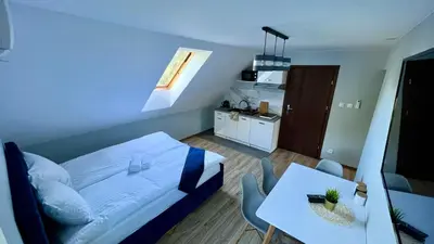 a bedroom with a bed and a table and a kitchen at Aparthotel w Dolinie Stawów Zator in Zator