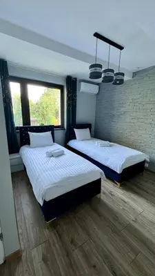 two beds in a room with two windows at Aparthotel w Dolinie Stawów Zator in Zator