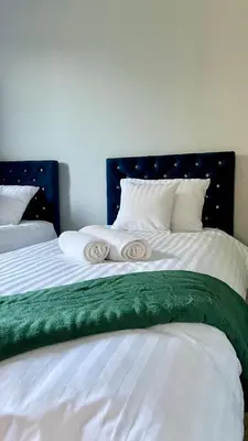 a bed with white sheets and a green blanket at Aparthotel w Dolinie Stawów Zator in Zator