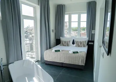 a bedroom with a bed and a tub and windows at Długa 17 Residence in Kraków