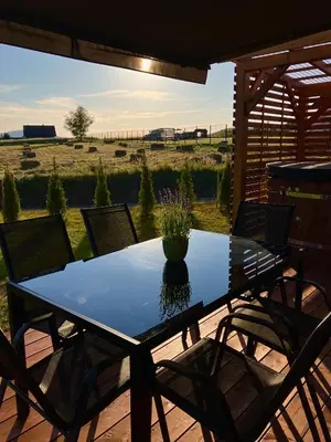 a table and chairs on a patio with a view of a field at Beskid Barns - Domek z Balią i Widokiem na Babią Górę in Jordanów