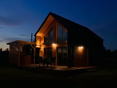 a small house with a deck at night at Beskid Barns - Domek z Balią i Widokiem na Babią Górę in Jordanów