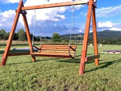 a swing seat in a field with a grass field at Beskid Barns - Domek z Balią i Widokiem na Babią Górę in Jordanów
